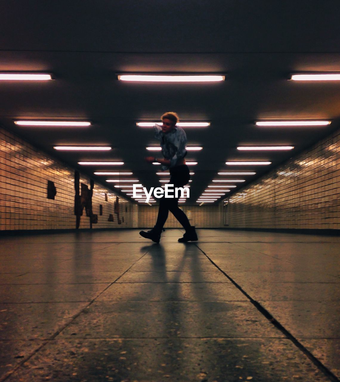 FULL LENGTH OF MAN WALKING IN ILLUMINATED UNDERGROUND