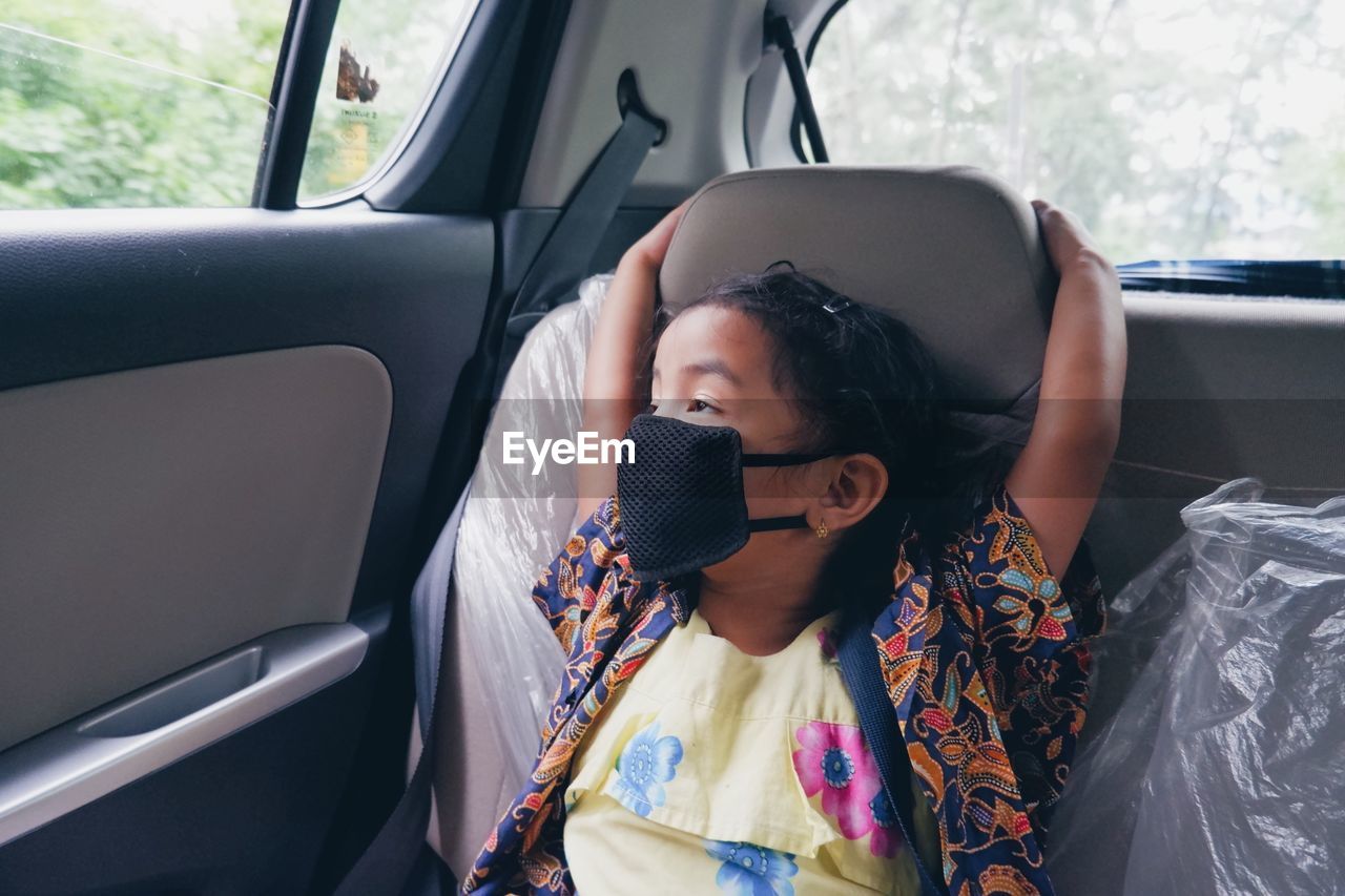 Young girl looking outside while sitting in car