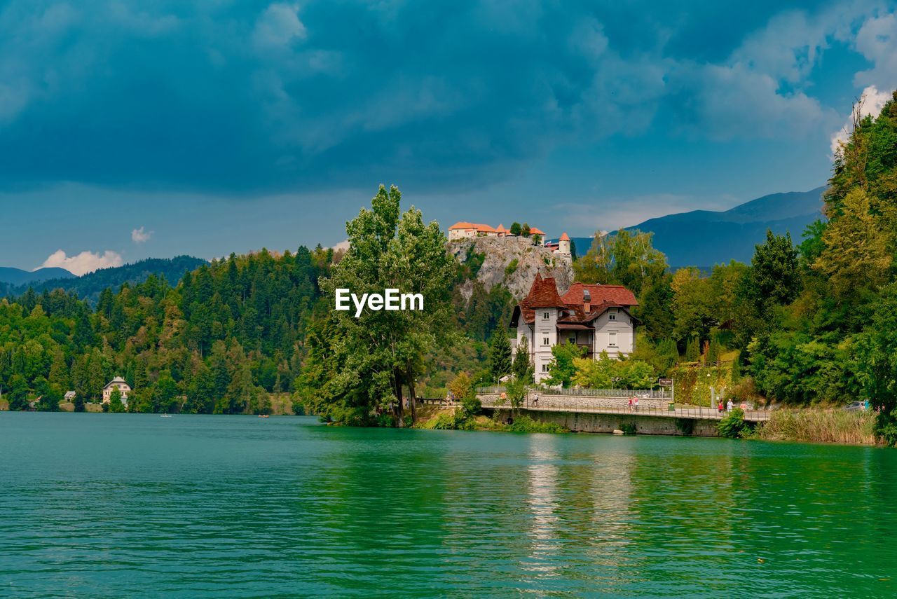 House on lake by building against sky