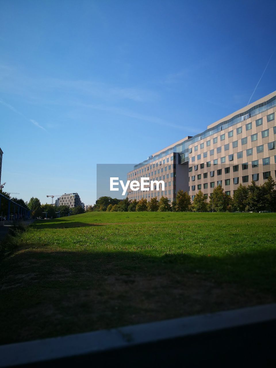 BUILDINGS ON FIELD AGAINST BLUE SKY