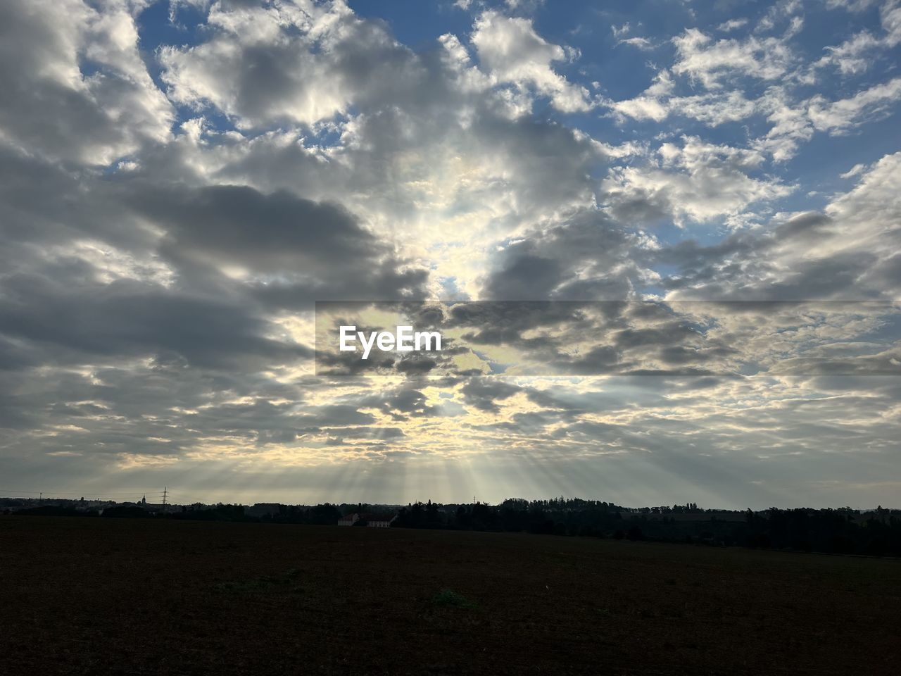 sky, cloud, horizon, environment, landscape, beauty in nature, nature, scenics - nature, sunlight, field, tranquility, sunset, land, sun, dusk, no people, tranquil scene, dramatic sky, cloudscape, evening, outdoors, plant, silhouette, rural scene, plain, horizon over land, idyllic, non-urban scene, sunbeam, blue, tree