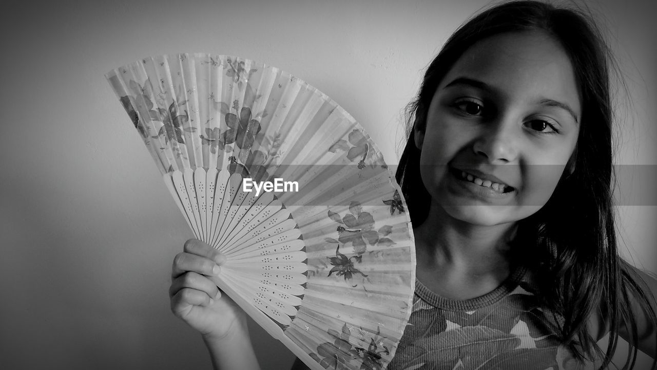 Portrait of smiling girl holding folding fan