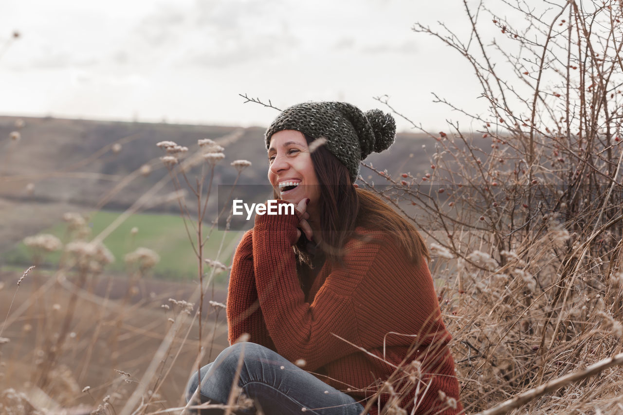 Woman looking away while sitting on land