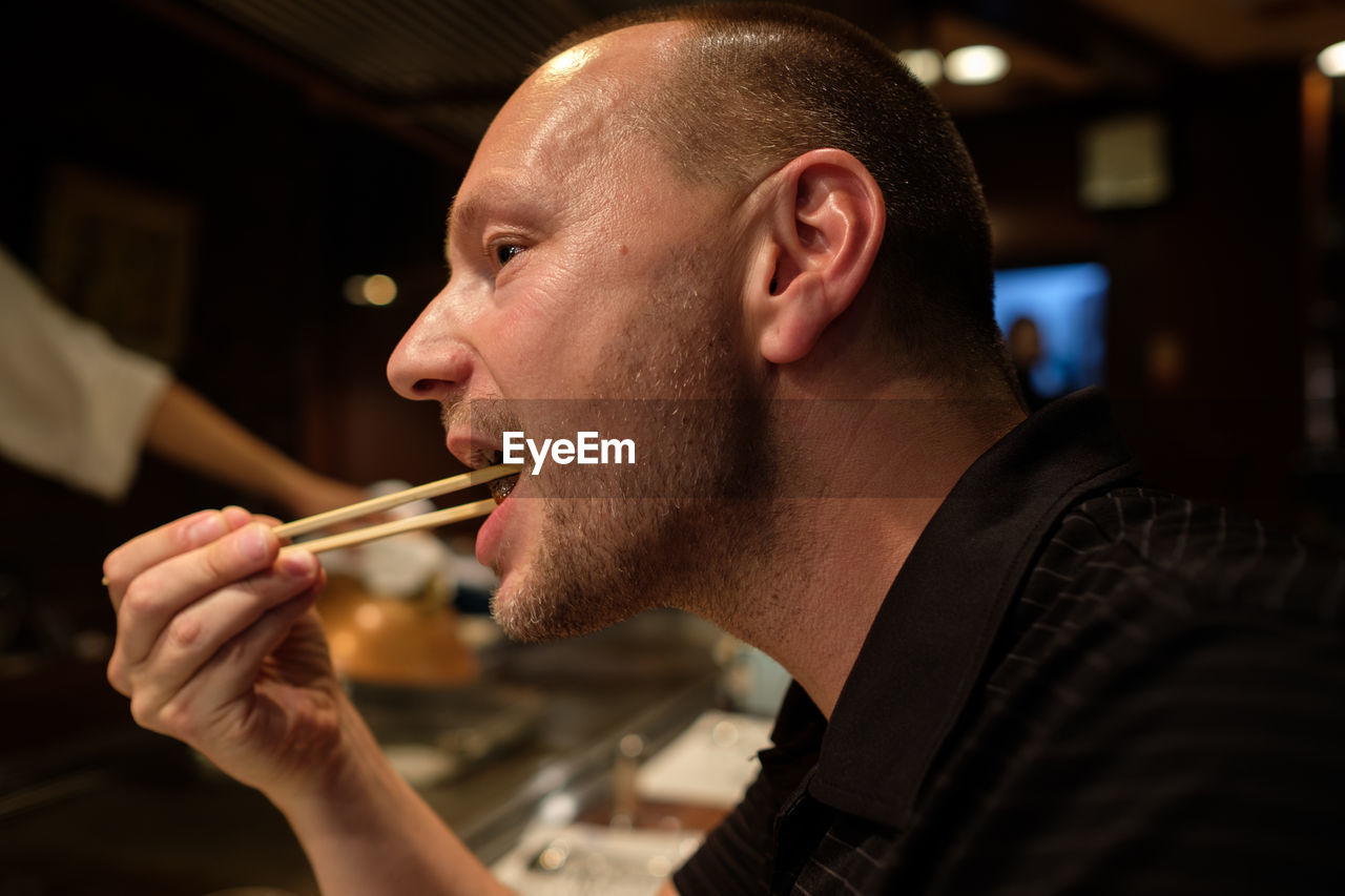 Close-up of man eating with chopsticks