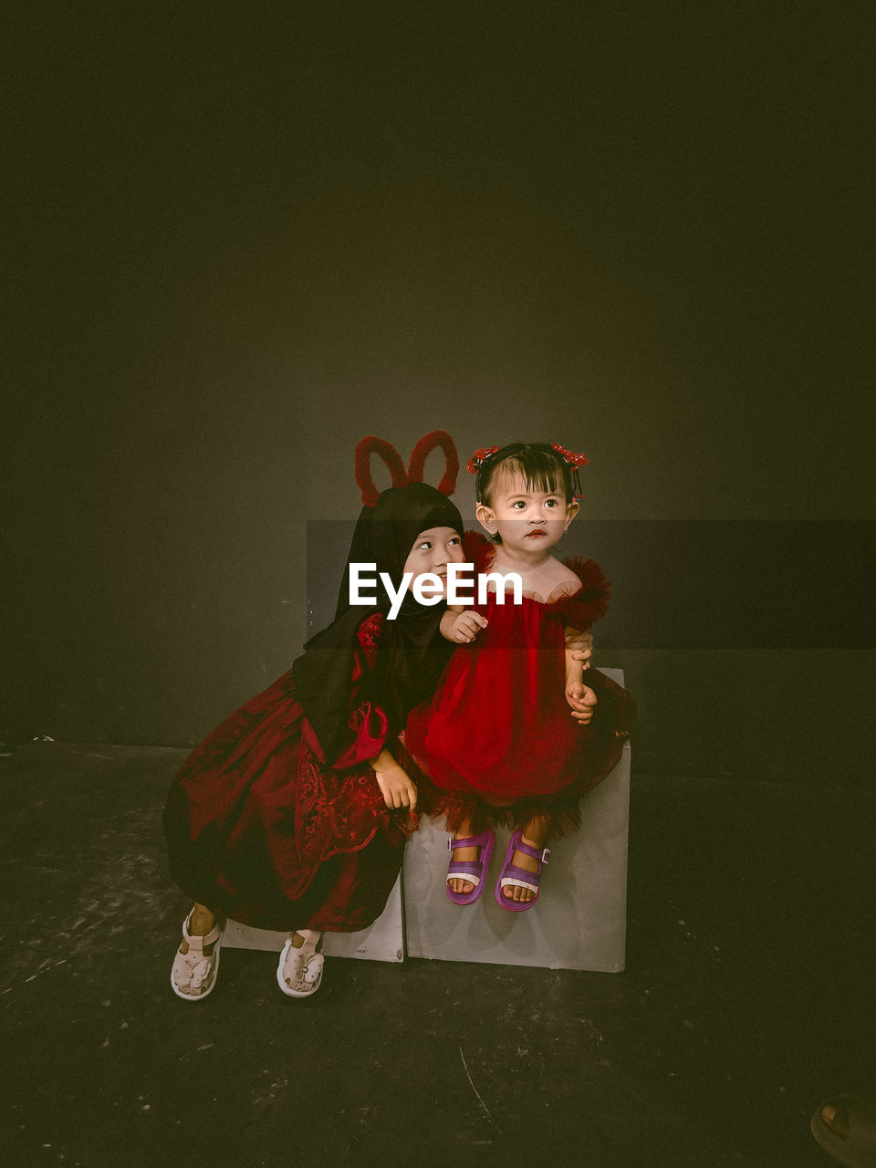 Two beautiful little girls wearing maroon dresses