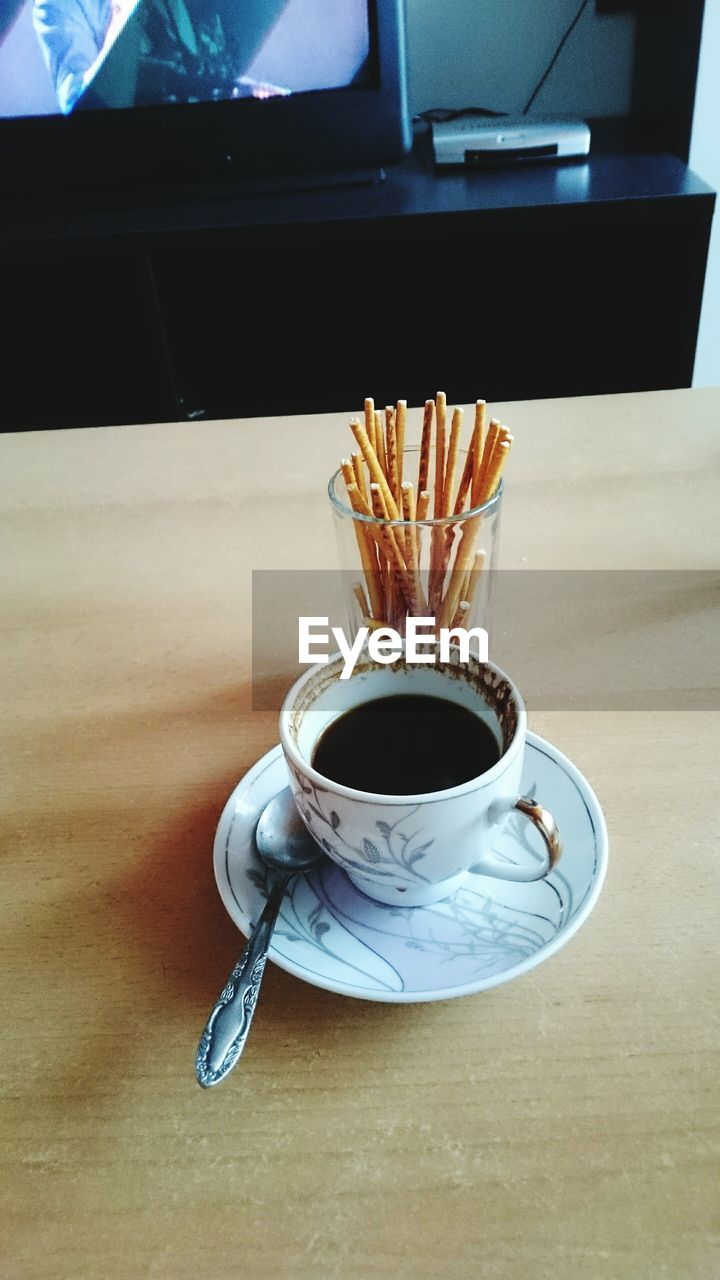 Close-up of black coffee with breadsticks on table