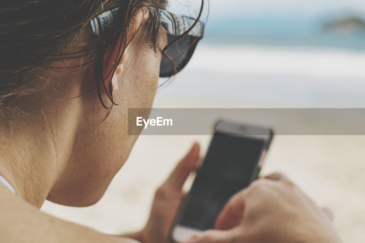 Close-up of woman using mobile phone at beach