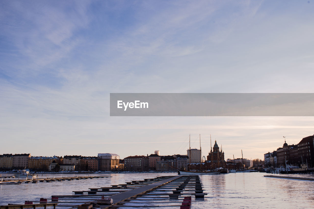 View of buildings at waterfront against cloudy sky