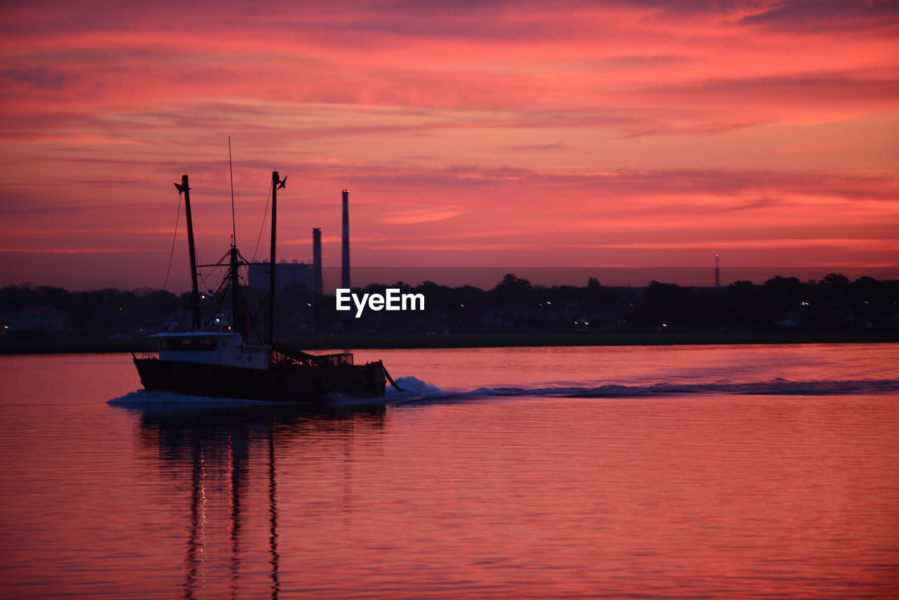 Boat sailing on sea against sky during sunset