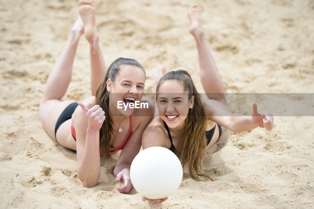 PORTRAIT OF SMILING YOUNG COUPLE ON SAND