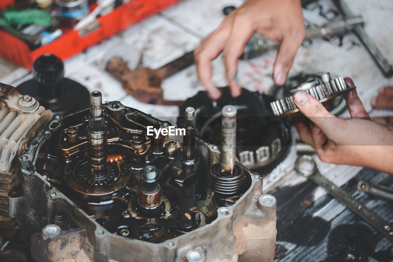 Cropped hands repairing engine in garage
