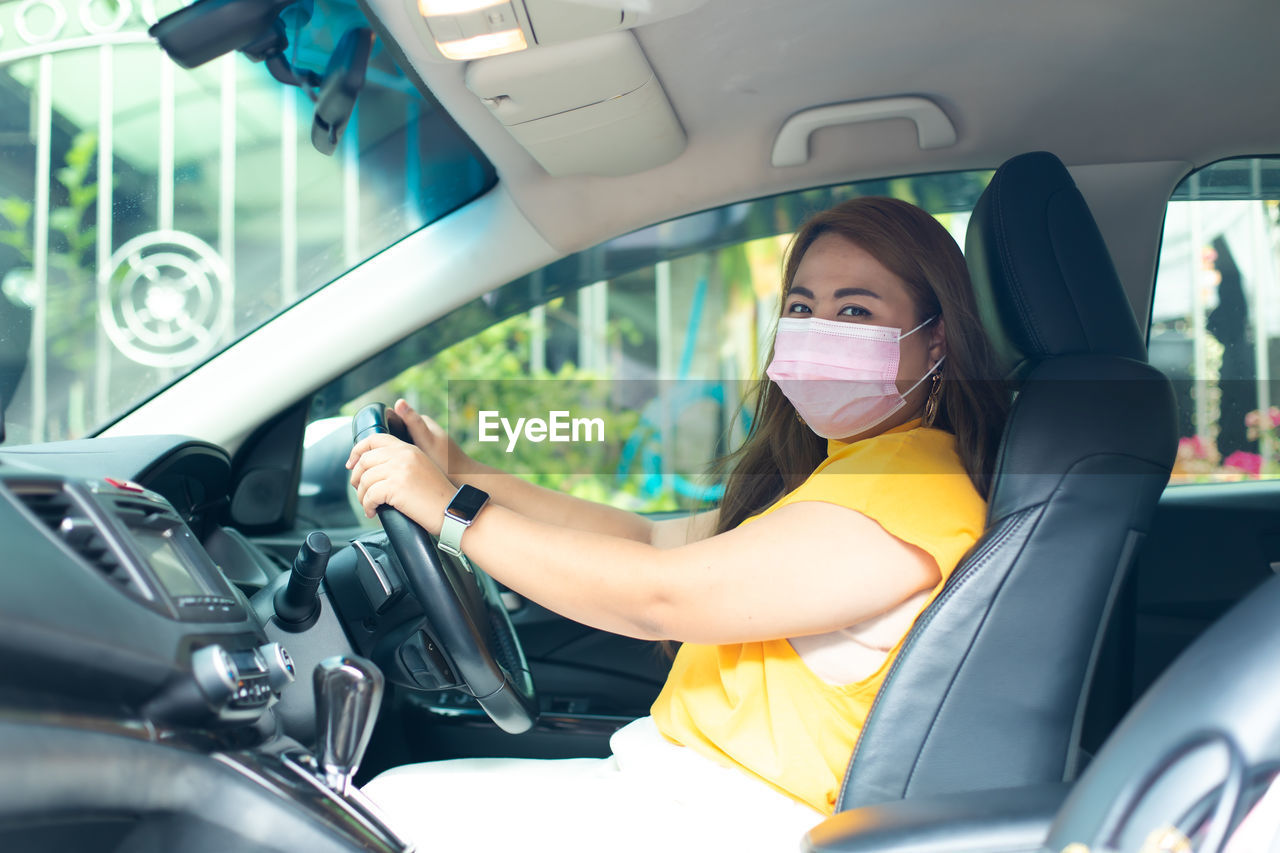 PORTRAIT OF YOUNG WOMAN USING LAPTOP IN CAR