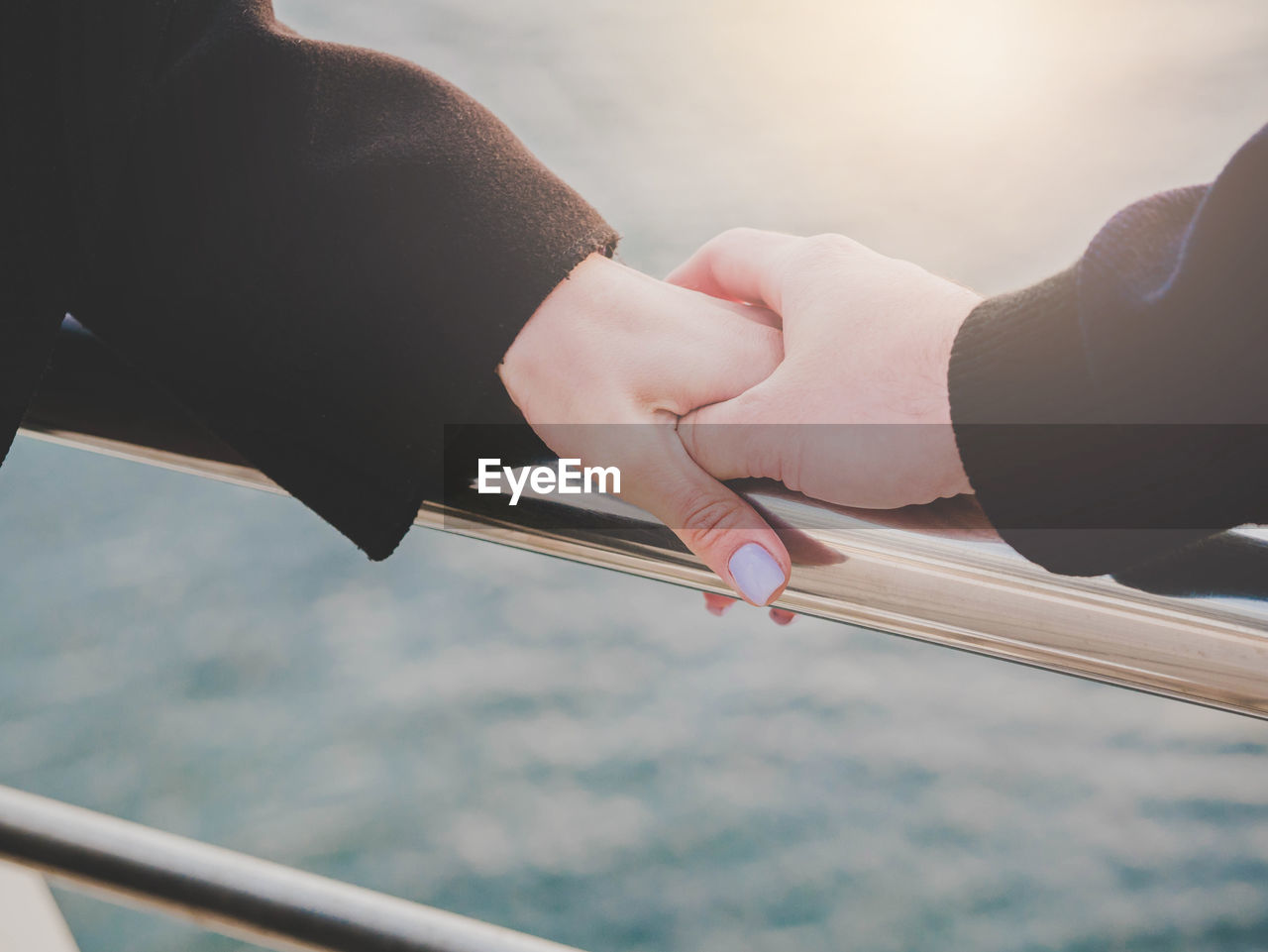 Cropped image of man holding hands of woman on railing