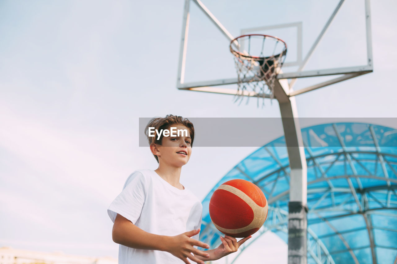 Boy playing with basketball at court