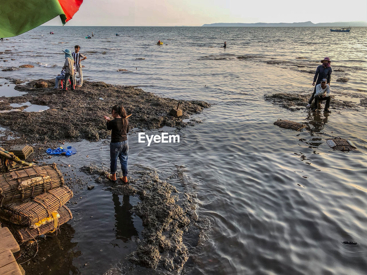 PEOPLE STANDING ON BEACH AGAINST SEA