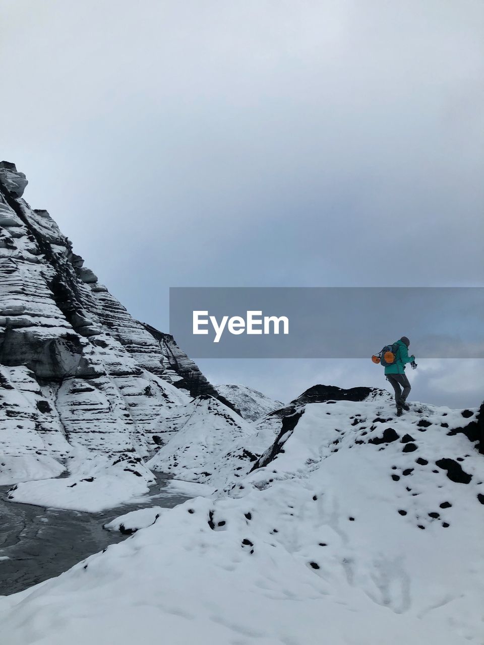 PERSON ON SNOWCAPPED MOUNTAIN AGAINST SKY