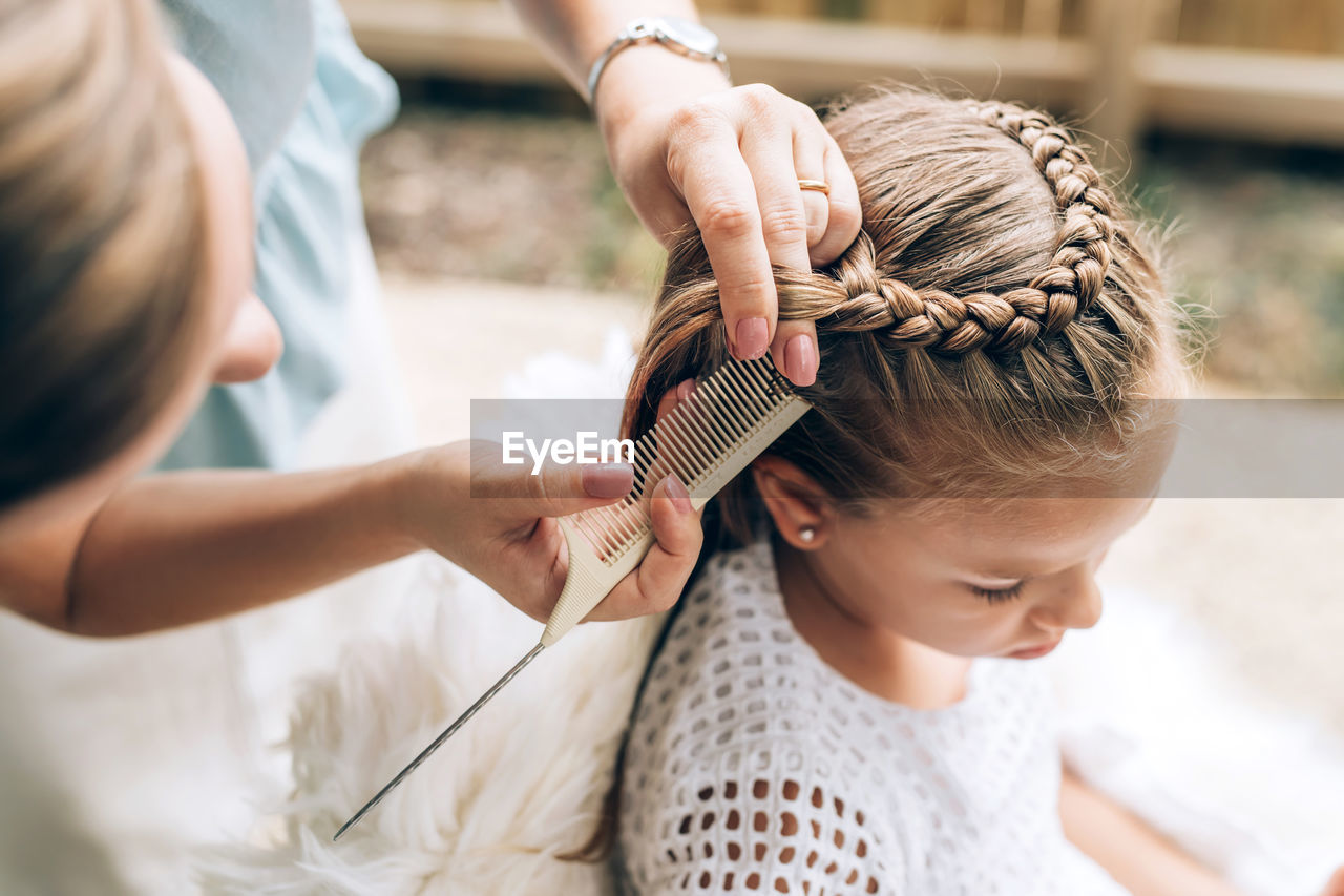 High angle view of woman hairstyling daughter