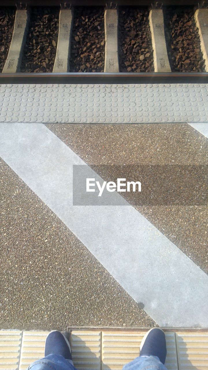 LOW SECTION OF PERSON STANDING ON RAILROAD TRACKS