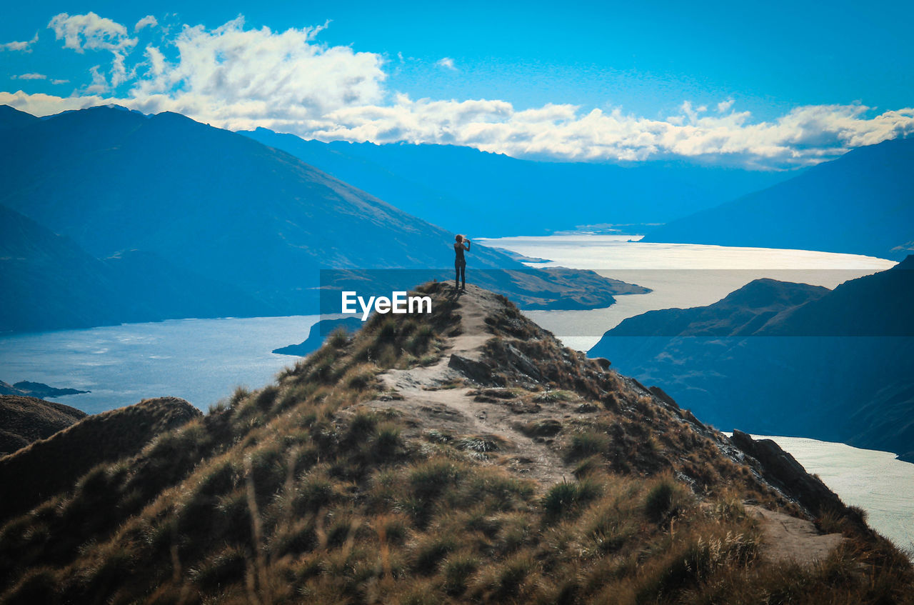 Woman standing on mountain against blue sky