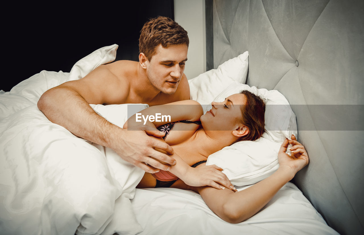 Young man embracing woman on bed at home