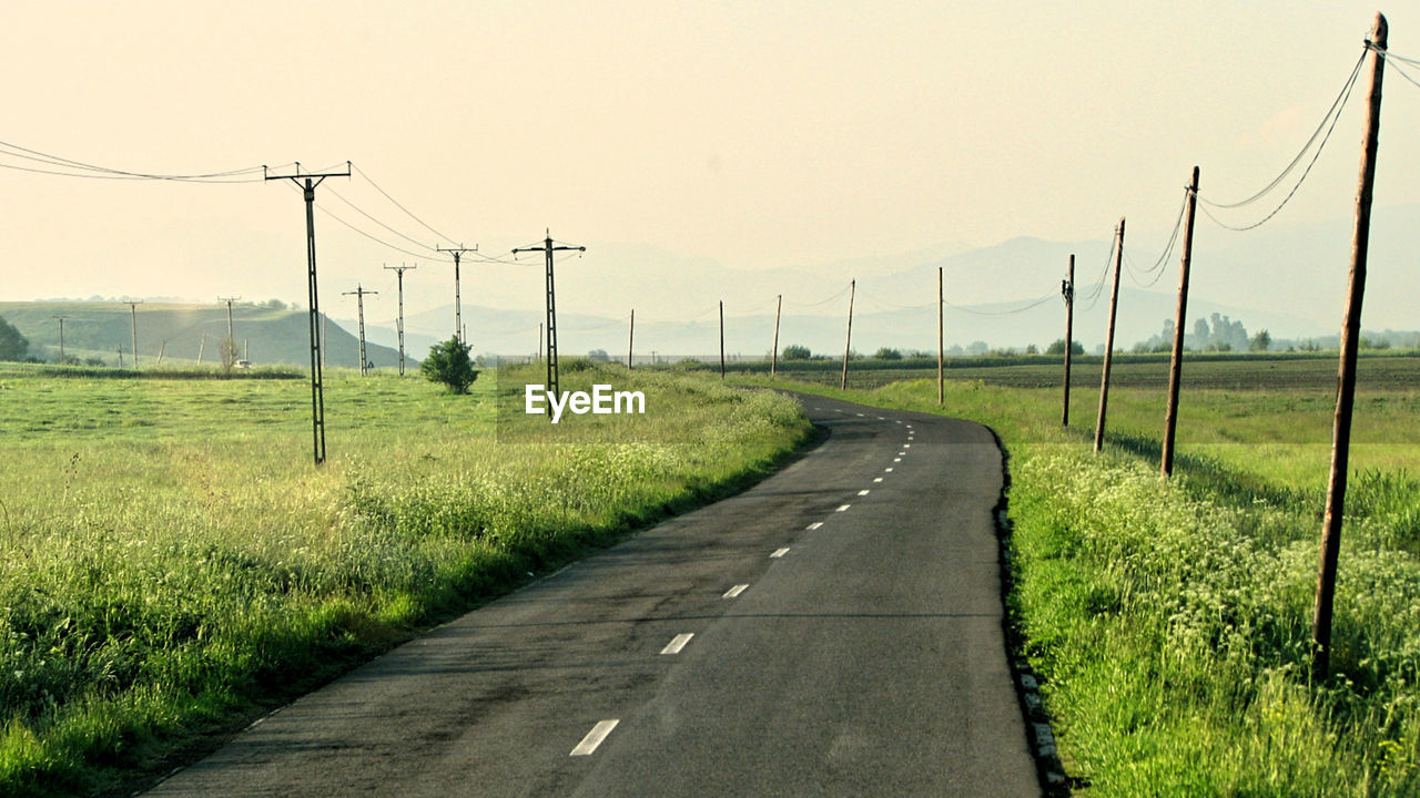 Road amidst field against clear sky