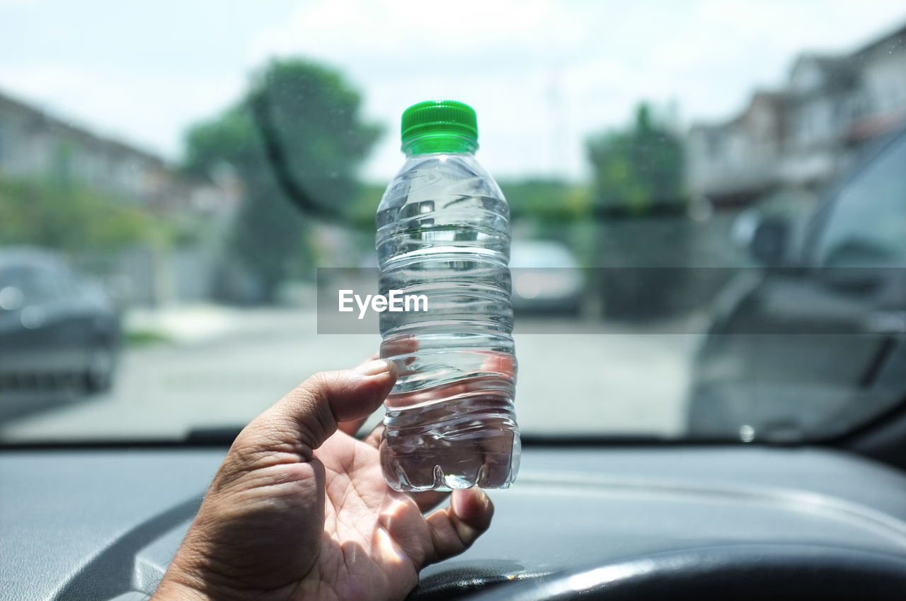 Person holding a mineral water bottle in the car