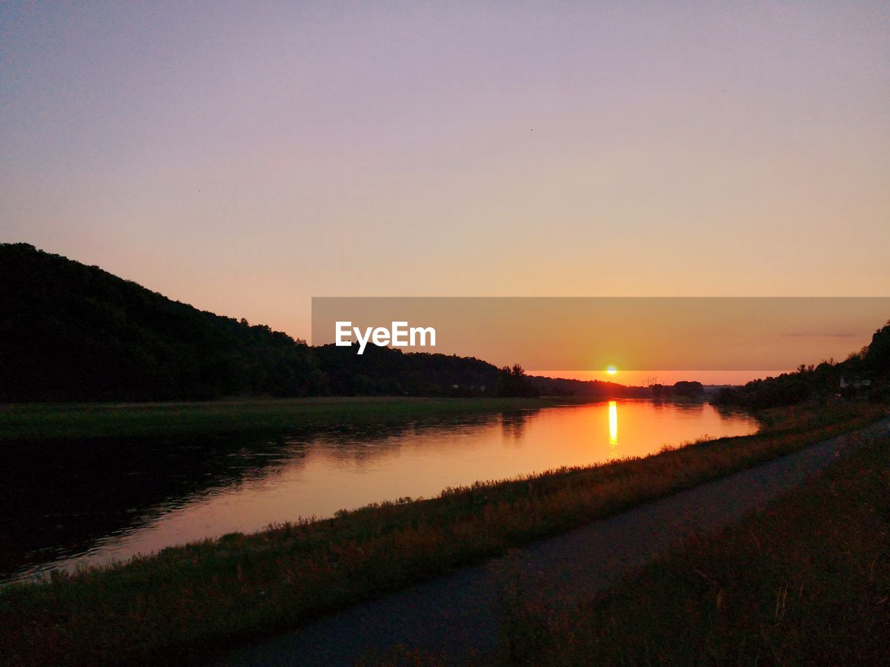 SCENIC VIEW OF LAKE AGAINST SKY AT SUNSET