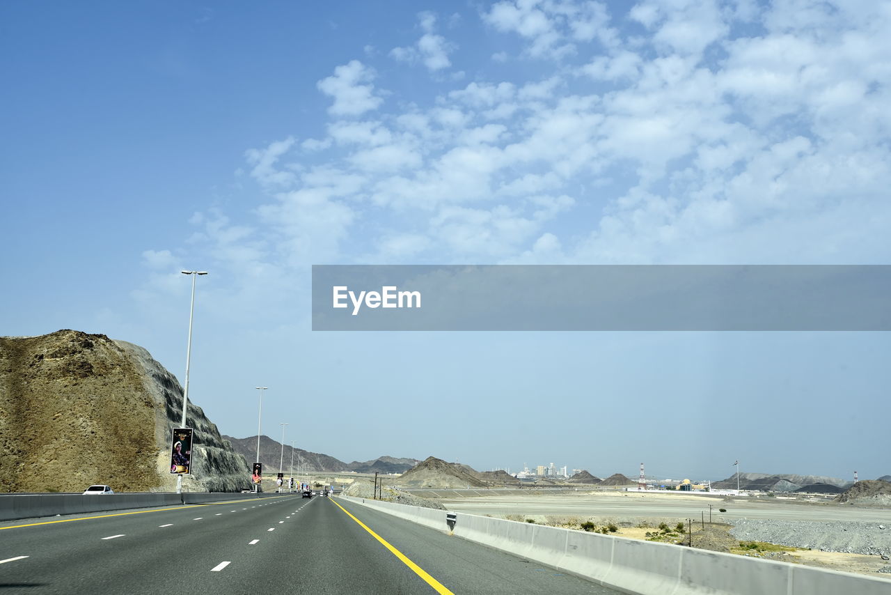 SURFACE LEVEL VIEW OF HIGHWAY AGAINST SKY