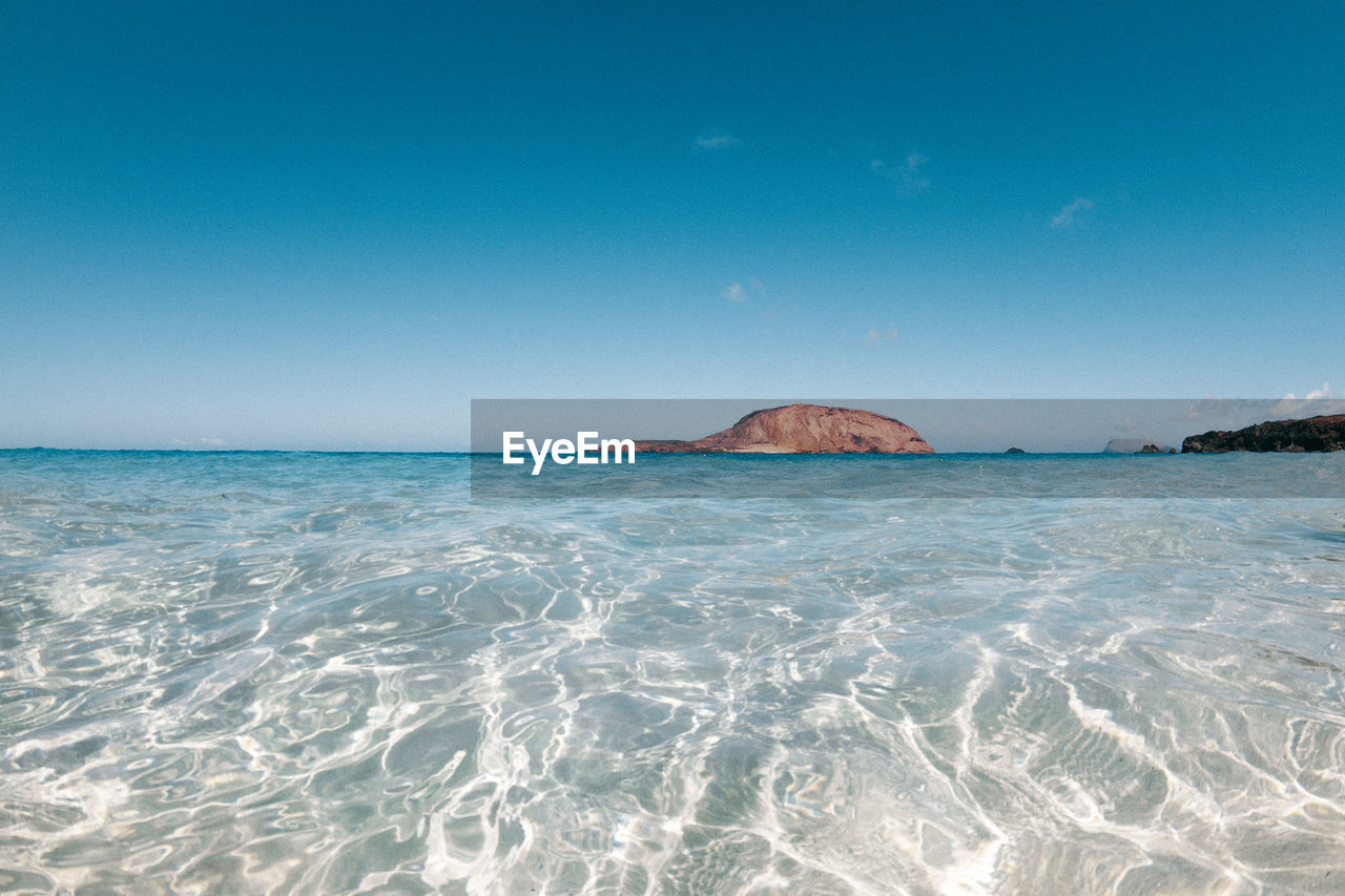 Scenic view of sea against clear blue sky