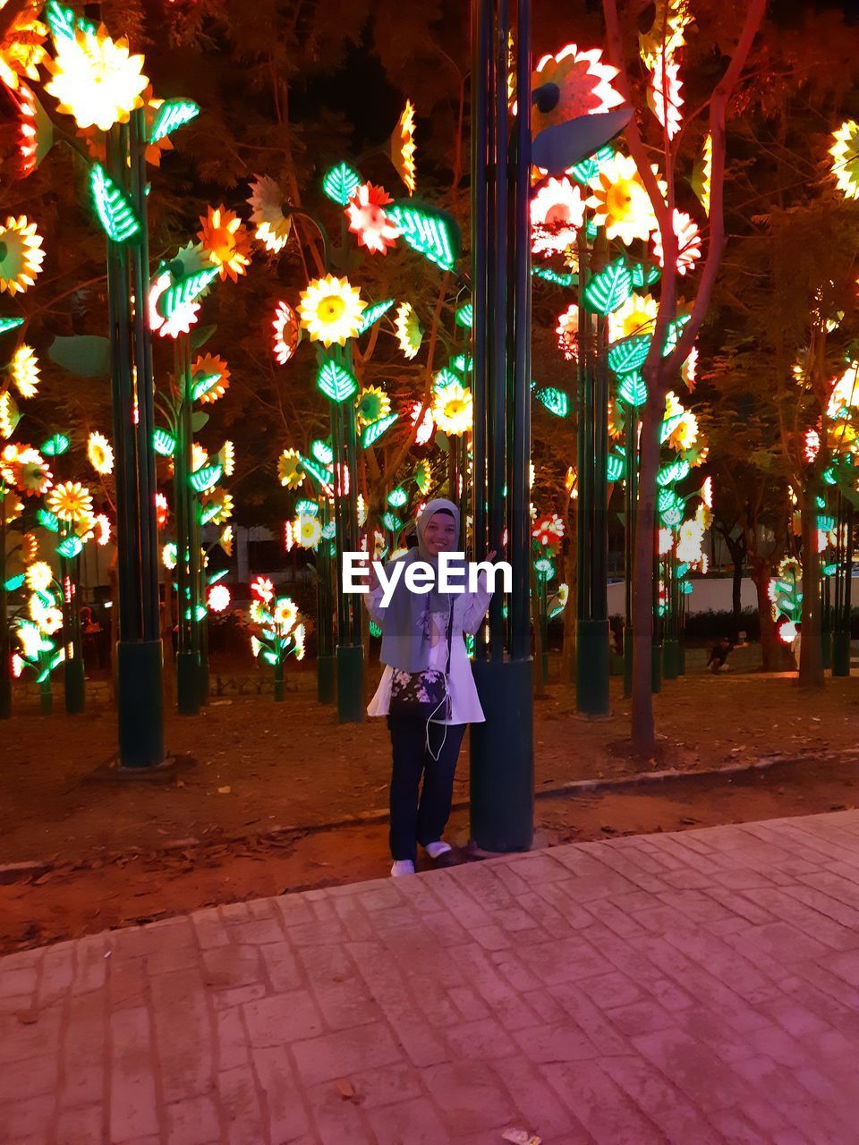 Full length of woman standing at illuminated decorative park during night