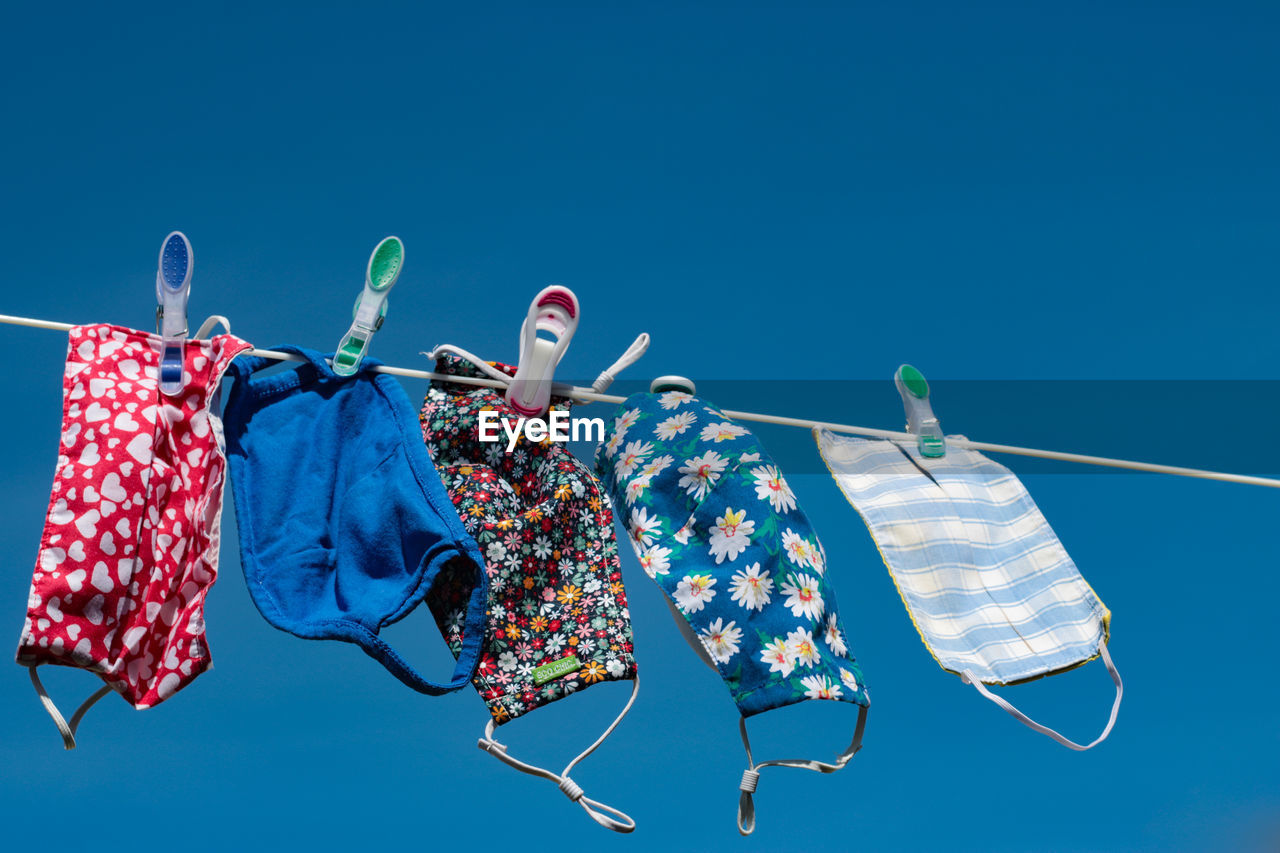 LOW ANGLE VIEW OF CLOTHES DRYING AGAINST BLUE SKY