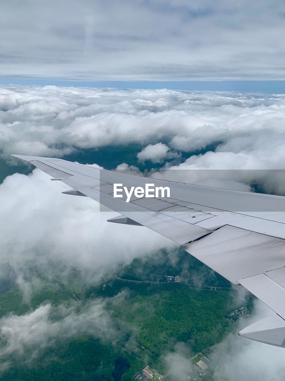 Aerial view of aircraft wing against cloudy sky