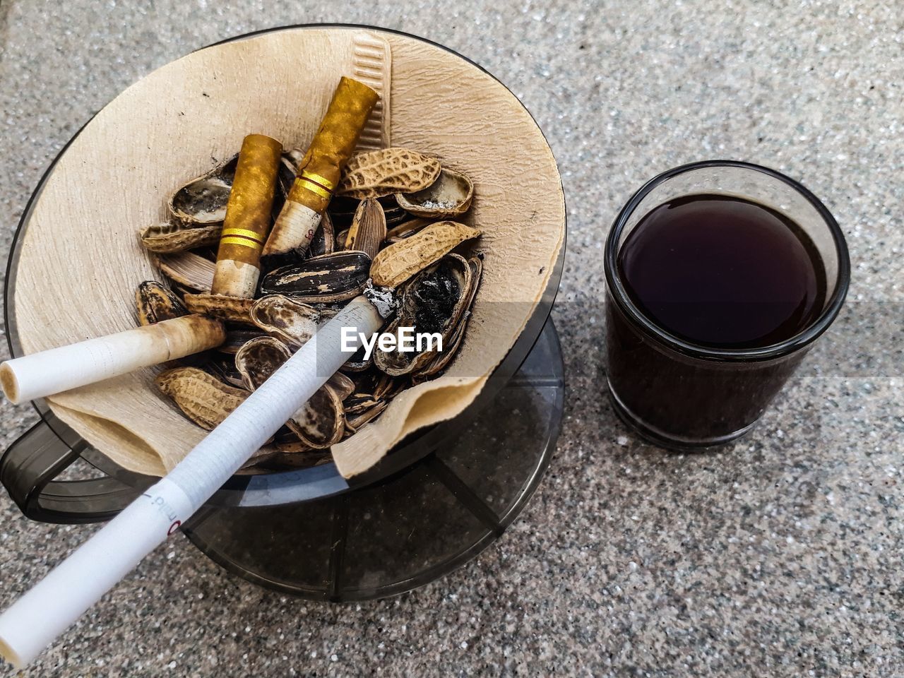 HIGH ANGLE VIEW OF CIGARETTE IN GLASS ON TABLE