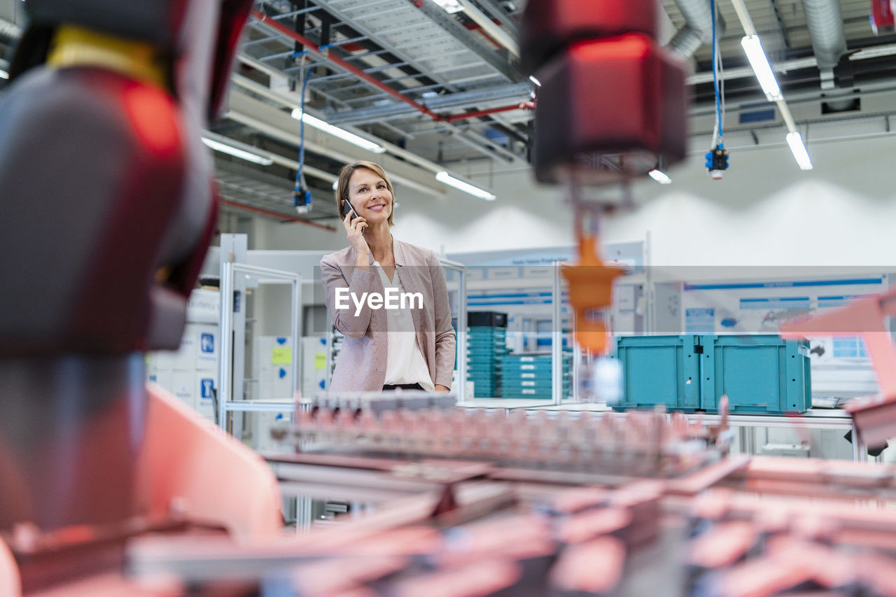 Businesswoman on cell phone in a modern factory hall