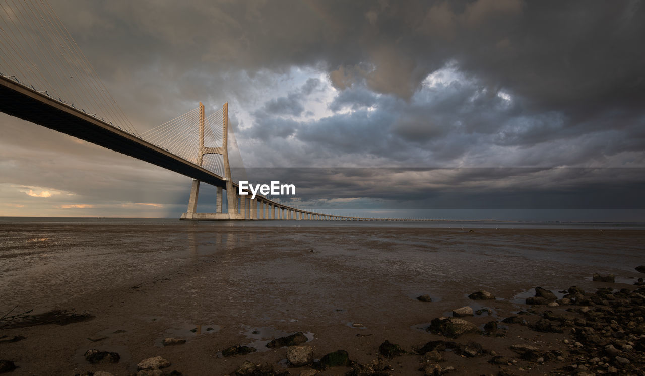 Vasco da gama bridge at sunset with dramatic cloudy sky in lisbon