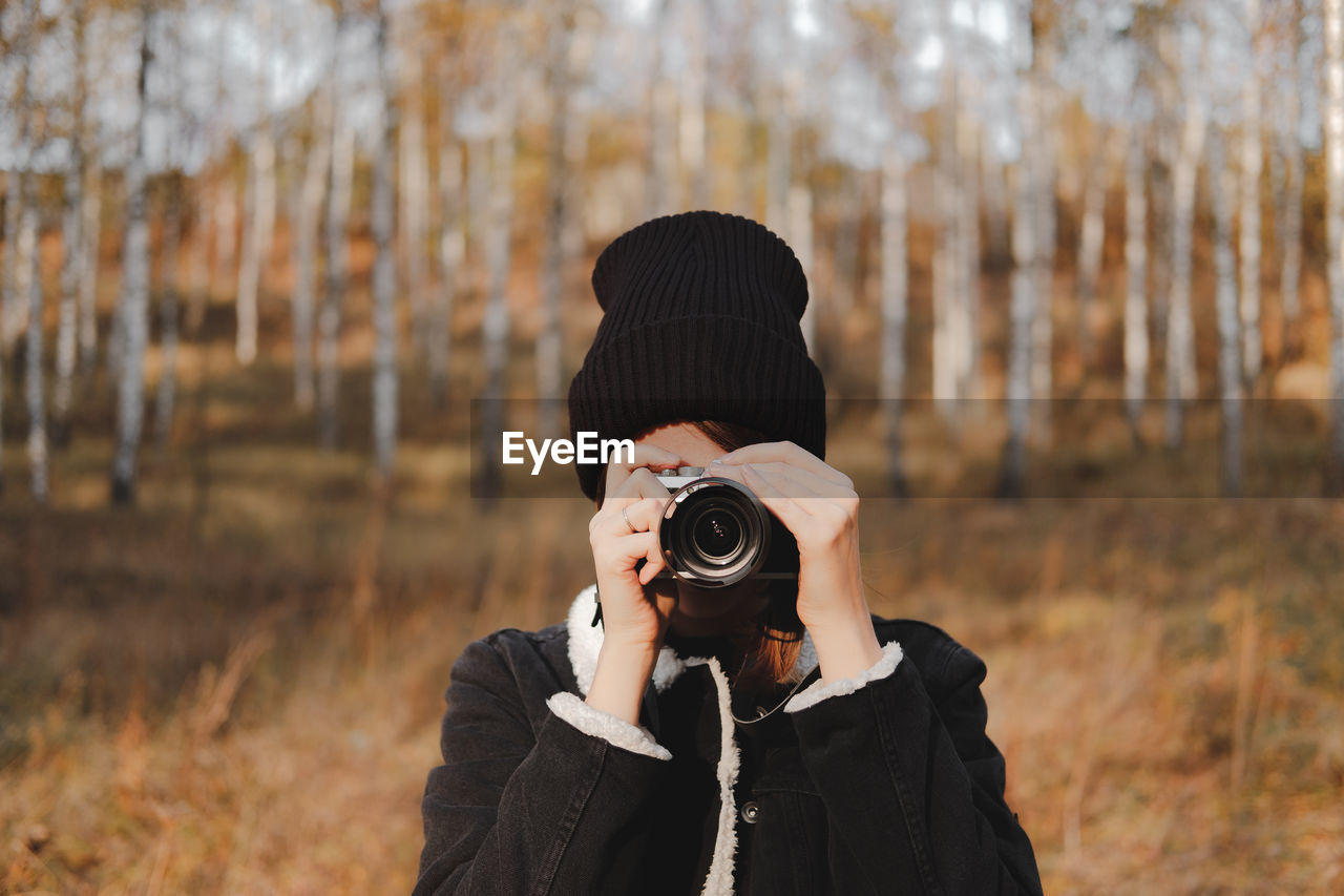 Portrait of a young woman with camera taking a picture in beauti