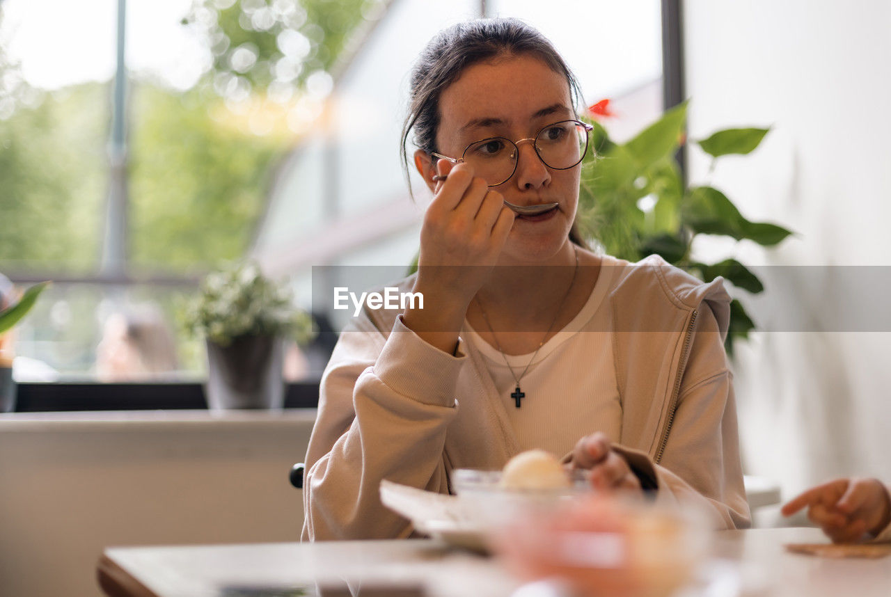 Portrait of a caucasian teenage girl with ice cream in a cafe.