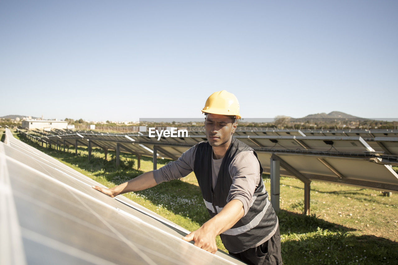 Young male maintenance engineer repairing solar panels at power station