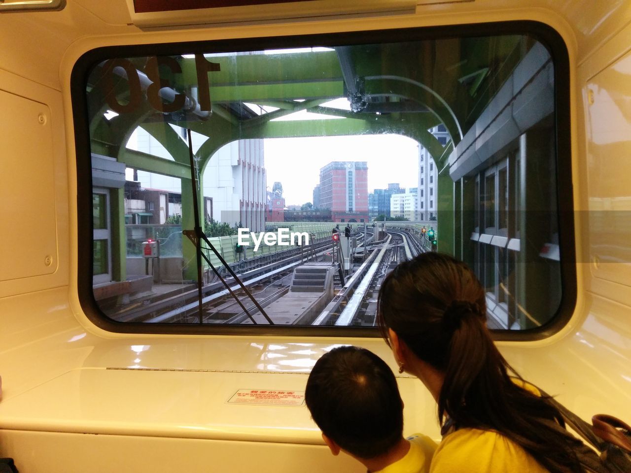 Side view of mother with son looking through train window