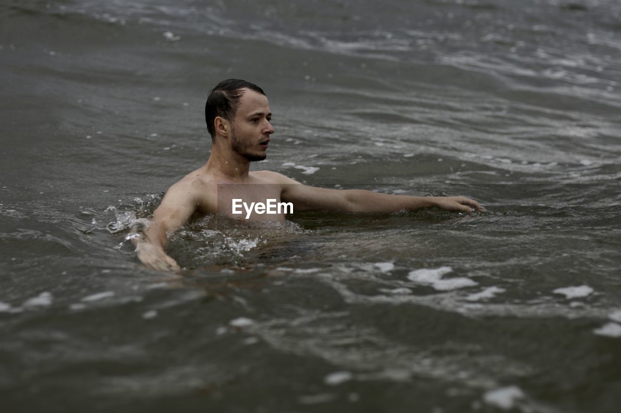 FULL LENGTH OF SHIRTLESS MAN IN SEA