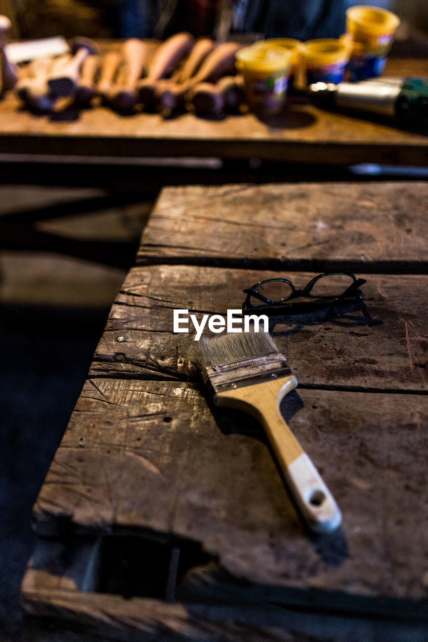 Close-up of paintbrush and eyeglasses on wooden table