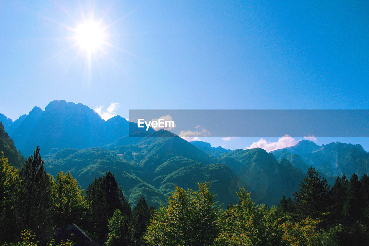 Scenic view of mountains against blue sky on sunny day