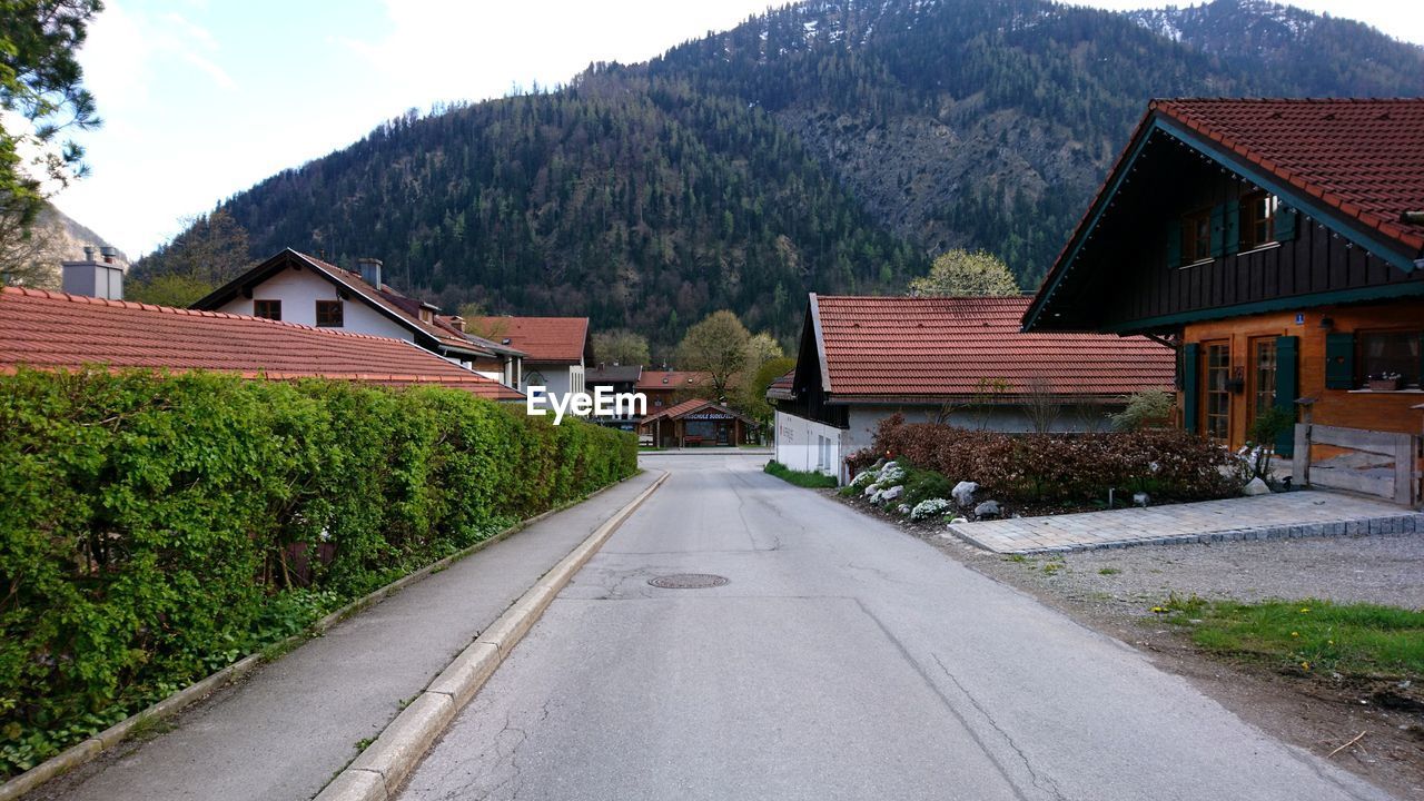 Road amidst houses against sky