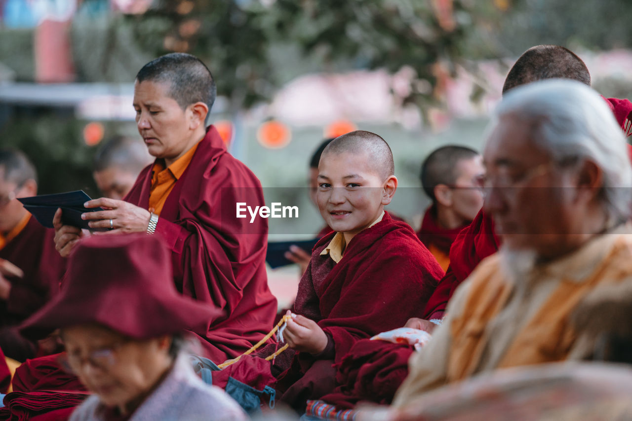 GROUP OF PEOPLE LOOKING AT CAMERA WHILE SITTING ON PHONE