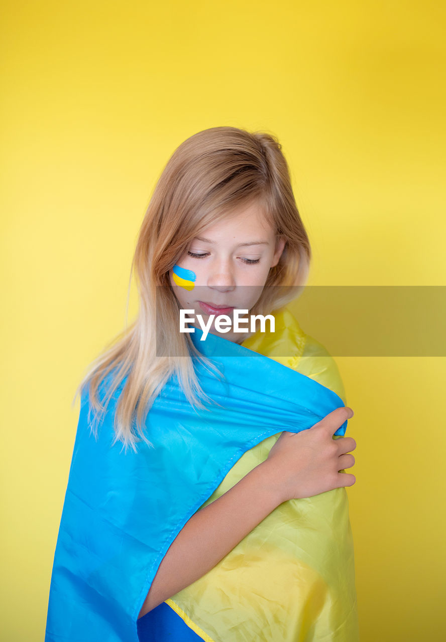 Portrait of young woman against yellow background