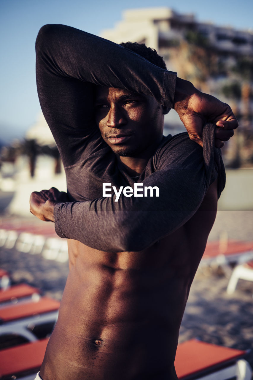 Young man removing t-shirt at beach