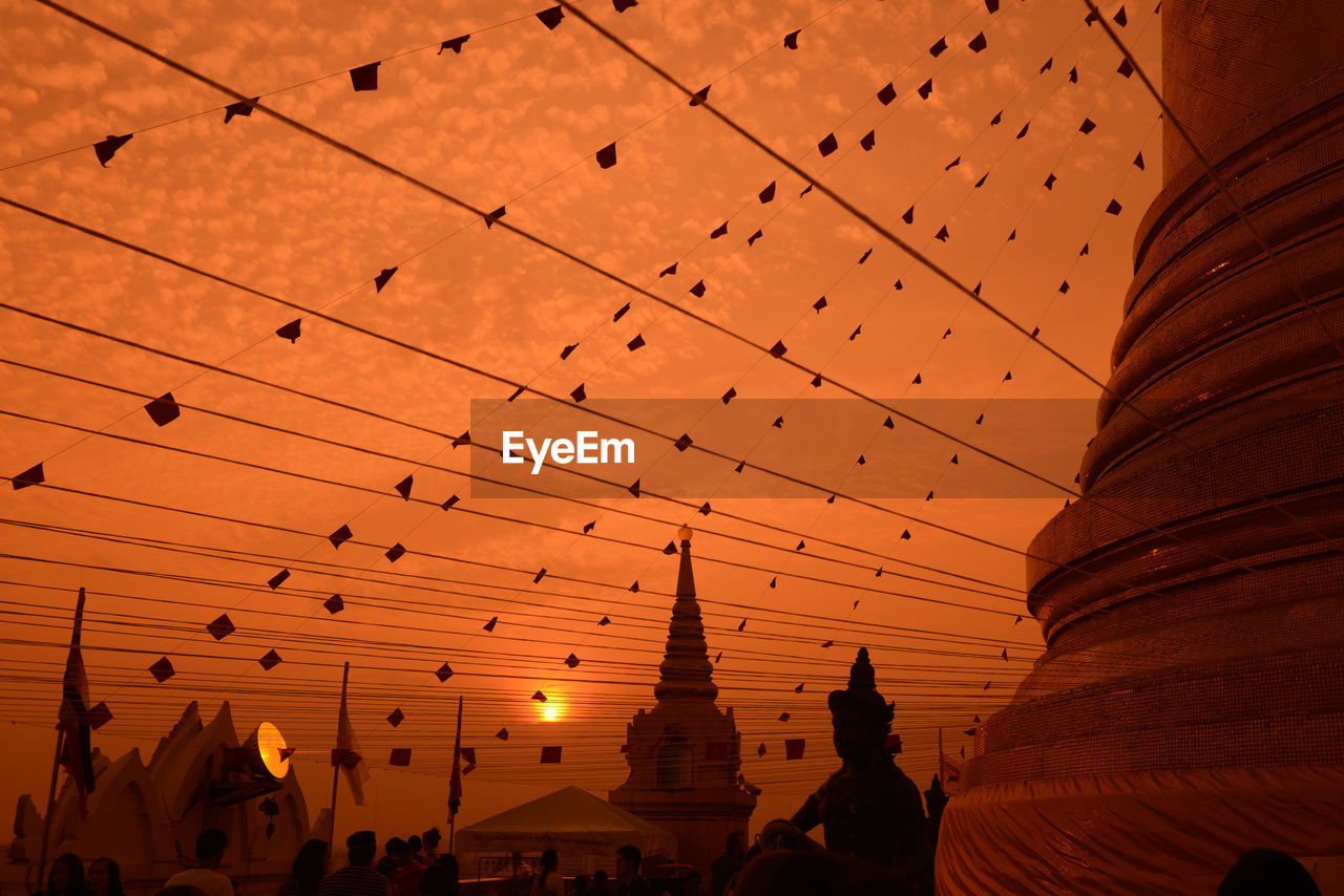 Low angle view of decorations at temple against orange sky during sunset