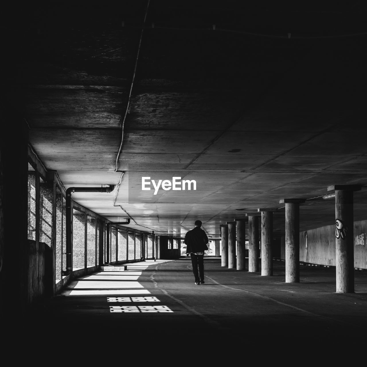 Rear view of man walking below bridge