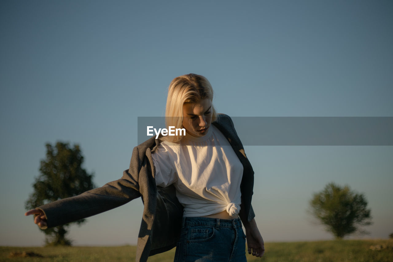 Portrait of a young woman putting on a jacket