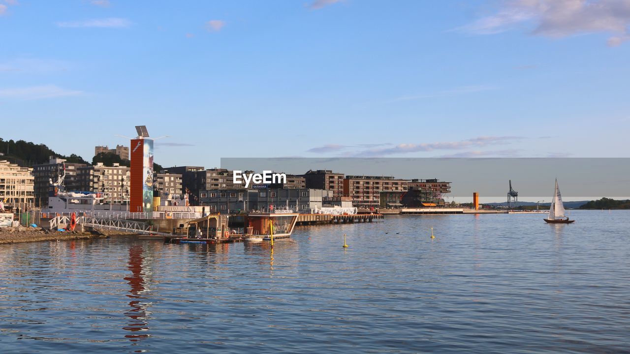 SAILBOATS IN SEA AGAINST BUILDINGS IN CITY